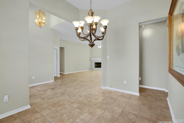 interior space with a fireplace, a notable chandelier, and baseboards