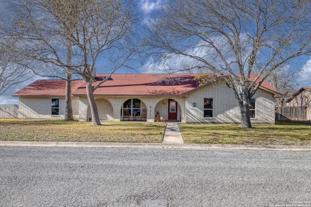 view of front of home featuring covered porch, a front lawn, fence, and brick siding