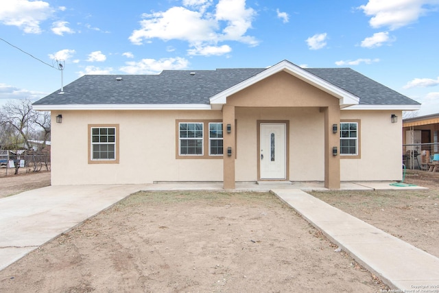 view of front of property with a shingled roof, fence, and stucco siding