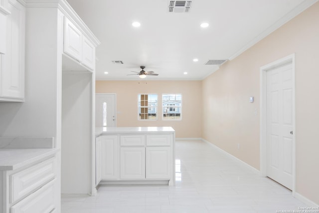 kitchen with light countertops, white cabinets, visible vents, and crown molding