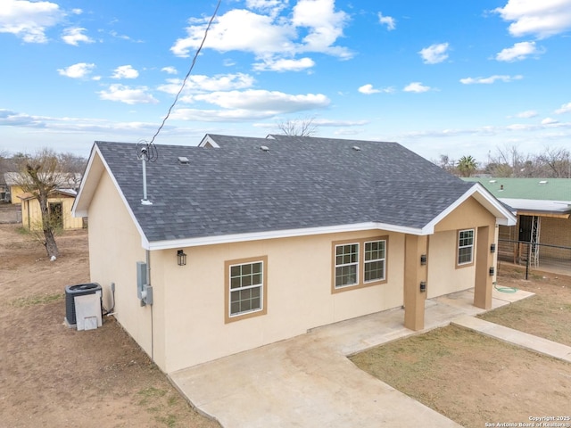 rear view of property with a patio, a shingled roof, cooling unit, and stucco siding