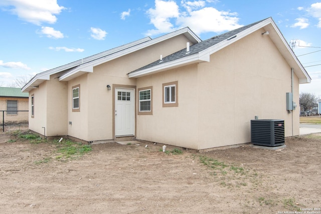 back of property featuring stucco siding, fence, and central air condition unit