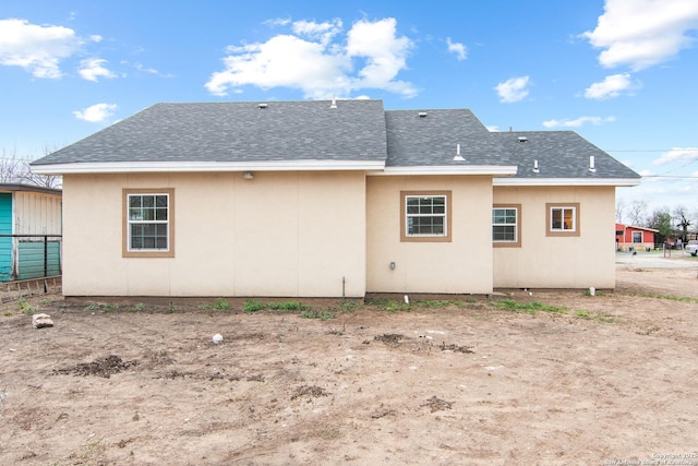 rear view of property with roof with shingles and stucco siding