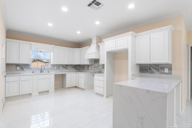 kitchen with a peninsula, a sink, visible vents, light stone countertops, and custom range hood