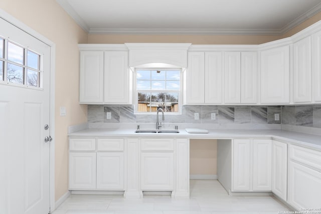 kitchen featuring ornamental molding, a sink, light countertops, white cabinetry, and backsplash