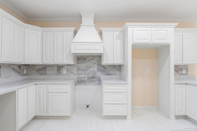 kitchen with baseboards, decorative backsplash, light countertops, crown molding, and white cabinetry