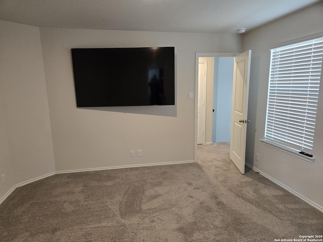 carpeted spare room featuring a wealth of natural light and baseboards