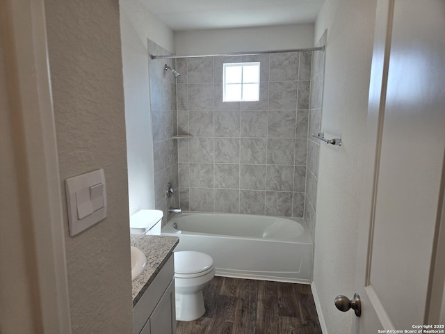 bathroom with a textured wall, shower / tub combination, toilet, wood finished floors, and vanity