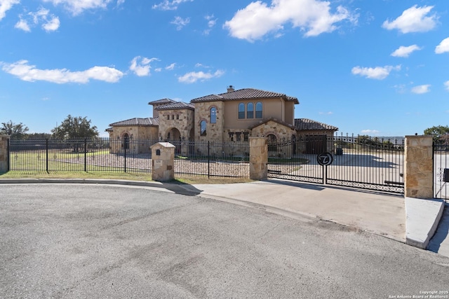 mediterranean / spanish-style home with stone siding, a chimney, a fenced front yard, and stucco siding