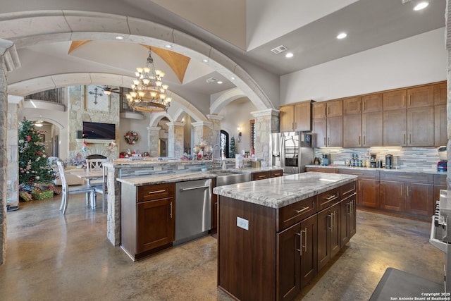 kitchen with finished concrete flooring, visible vents, a kitchen island with sink, stainless steel appliances, and a sink