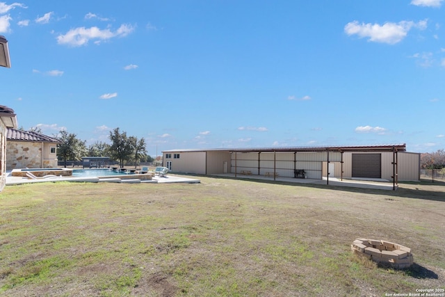 view of yard with an outbuilding, an outdoor pool, and a fire pit