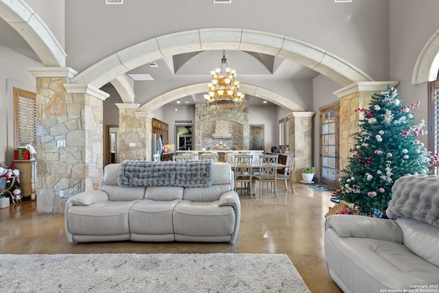 living area with ornate columns, a high ceiling, and a notable chandelier