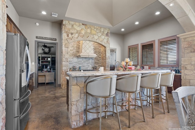 kitchen with stainless steel fridge, visible vents, a kitchen breakfast bar, concrete flooring, and recessed lighting