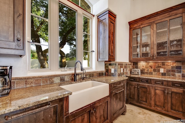 kitchen with a sink, backsplash, and light stone countertops