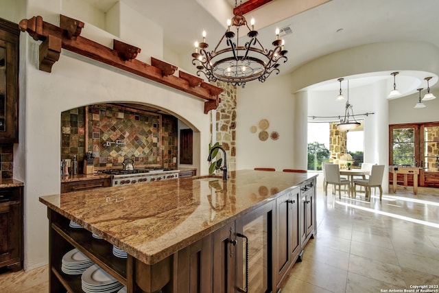 kitchen with wine cooler, light stone counters, a sink, open shelves, and backsplash