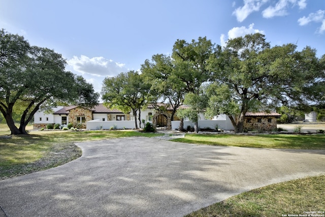 view of front of house with stone siding, a front yard, and driveway