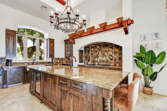 kitchen featuring light stone counters, visible vents, stainless steel gas cooktop, and a large island