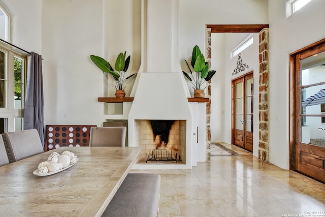 dining space with french doors, a fireplace, and a towering ceiling