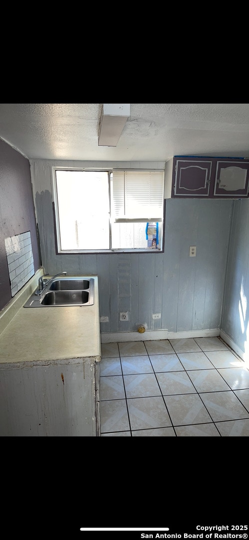 kitchen featuring light tile patterned floors, light countertops, and a sink