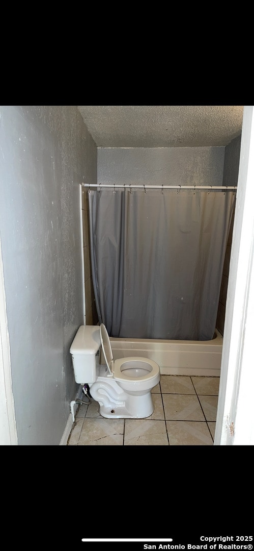 full bathroom featuring toilet, tile patterned flooring, and a textured ceiling