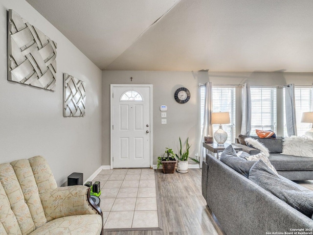 foyer with vaulted ceiling, plenty of natural light, light wood-style flooring, and baseboards