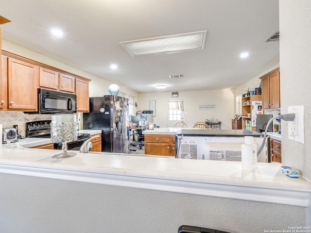 kitchen with a peninsula, black microwave, stainless steel refrigerator with ice dispenser, and range with electric stovetop