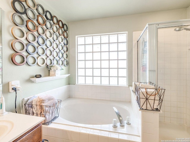 bathroom with a tile shower, a bath, and vanity