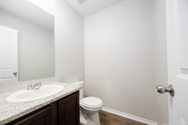 half bath with baseboards, vanity, toilet, and wood finished floors