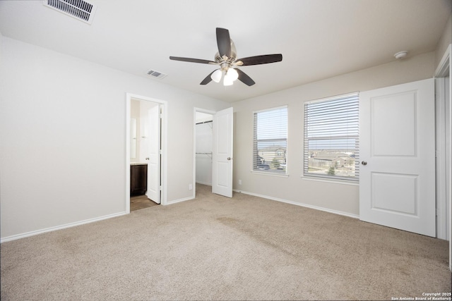 unfurnished bedroom with a spacious closet, carpet, visible vents, and baseboards