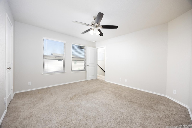 empty room with baseboards, ceiling fan, and light colored carpet