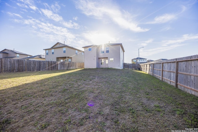 back of house with a fenced backyard and a lawn