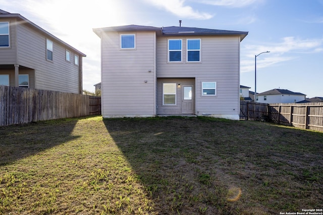 rear view of house with a fenced backyard and a yard