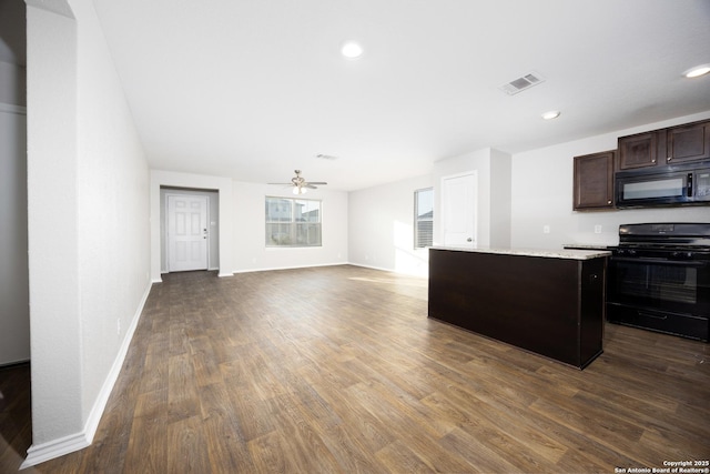 kitchen featuring visible vents, a kitchen island, dark wood-style flooring, light countertops, and black appliances