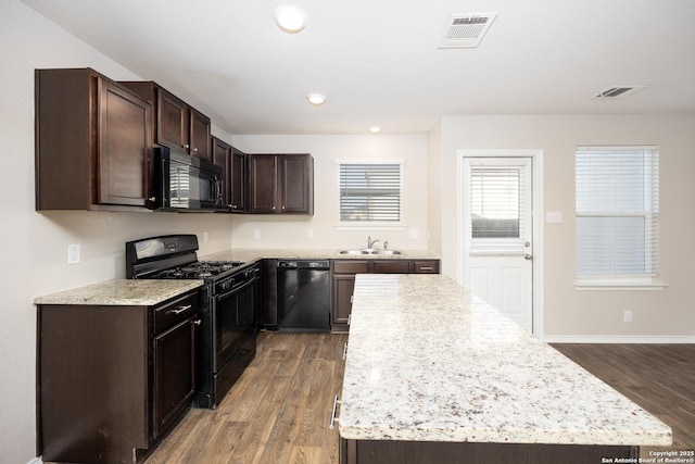 kitchen featuring light wood-type flooring, visible vents, a sink, and black appliances