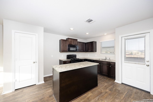 kitchen with dark brown cabinetry, a sink, visible vents, black appliances, and dark wood finished floors