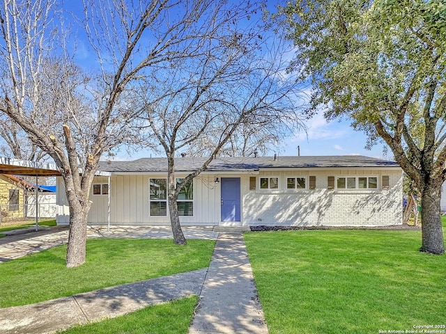 ranch-style house featuring brick siding, board and batten siding, a front yard, fence, and an attached carport