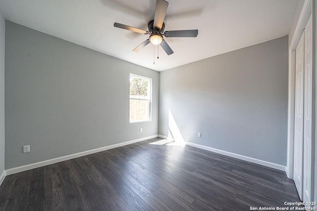 empty room with a ceiling fan, baseboards, and dark wood-style flooring