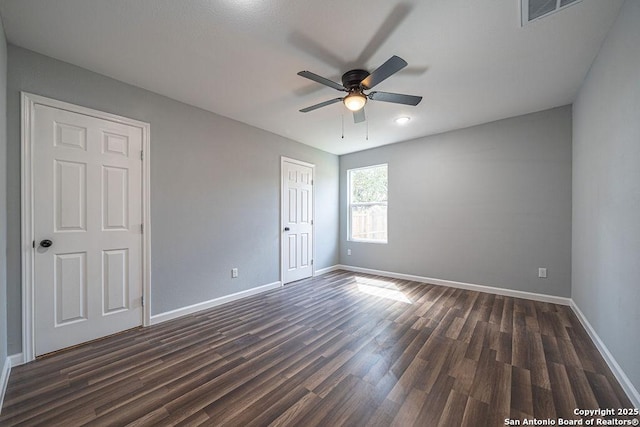 spare room featuring visible vents, dark wood finished floors, baseboards, and ceiling fan