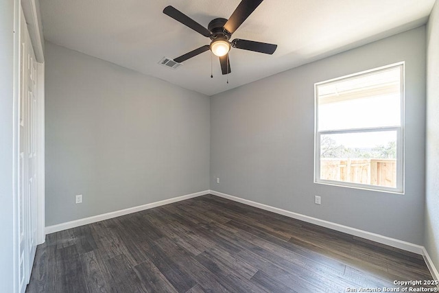 empty room with dark wood-style floors, ceiling fan, visible vents, and baseboards