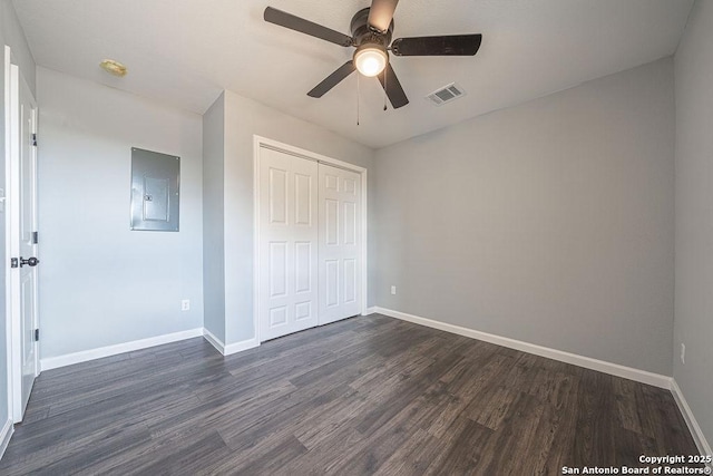 unfurnished bedroom featuring baseboards, electric panel, visible vents, and dark wood-style flooring