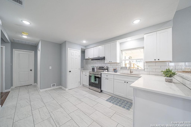 kitchen with under cabinet range hood, stainless steel electric range, white cabinets, and a sink