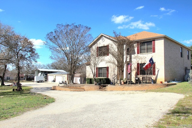 traditional home featuring a garage, brick siding, and an outbuilding