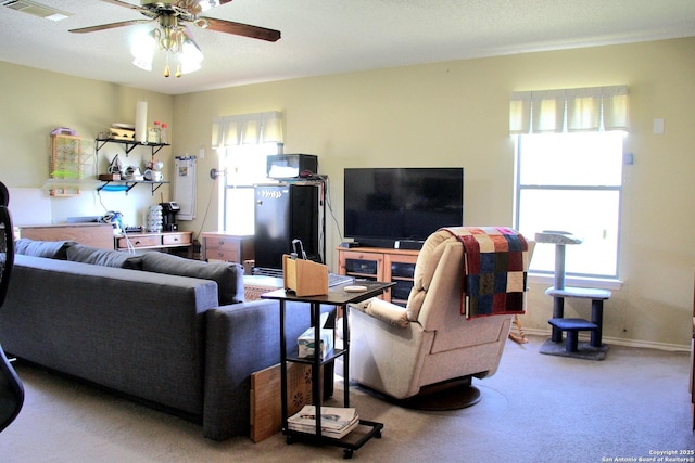 living room with carpet floors, baseboards, visible vents, and a ceiling fan