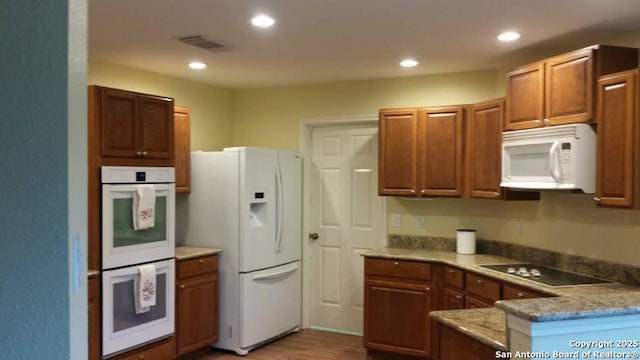 kitchen with white appliances, brown cabinets, visible vents, and recessed lighting