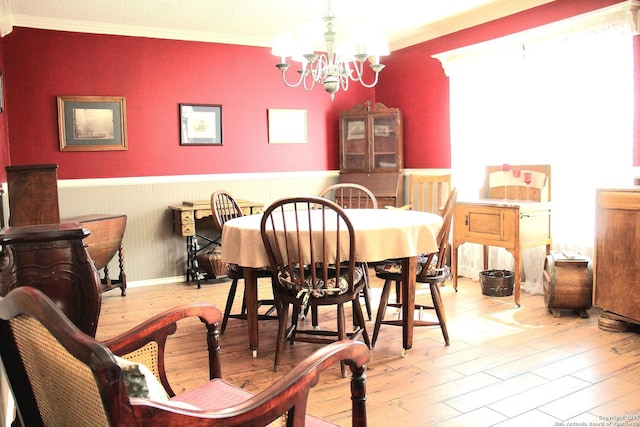 dining room with a notable chandelier, crown molding, wood finished floors, and wainscoting