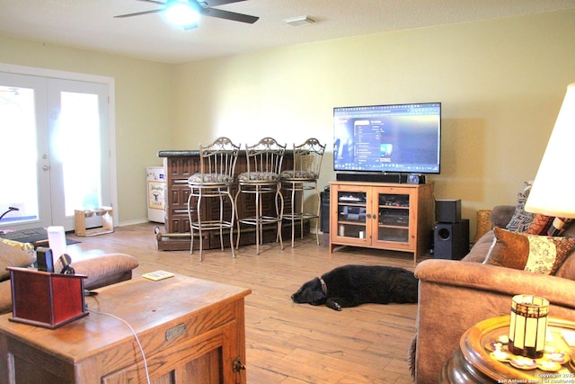 living area with visible vents, french doors, wood finished floors, and a ceiling fan