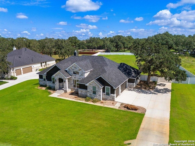 view of front of property with driveway, stone siding, a front yard, and fence