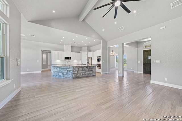 unfurnished living room with high vaulted ceiling, ceiling fan with notable chandelier, visible vents, light wood-style floors, and beamed ceiling