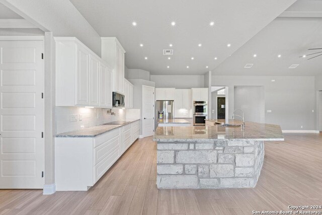 kitchen with a spacious island, visible vents, backsplash, appliances with stainless steel finishes, and a sink