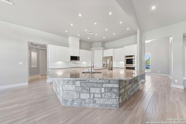 kitchen with appliances with stainless steel finishes, a high ceiling, a sink, and a large island with sink